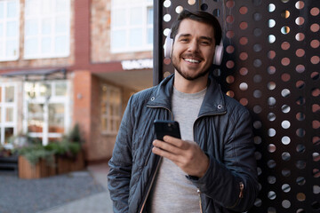 self-satisfied man in headphones listening to music and reading a message on a mobile phone