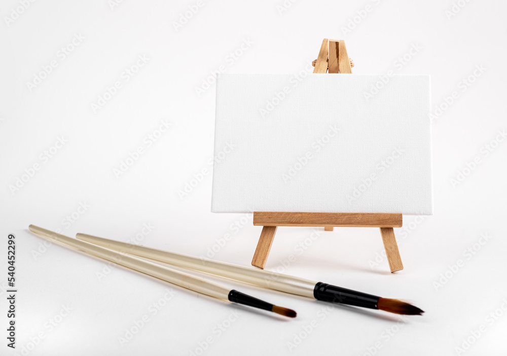 Poster mini easel with white blank empty horizontal canvas, paint brushes. art concept