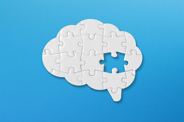 Mental health and problems with memory. Brain shaped white jigsaw puzzle on blue background.