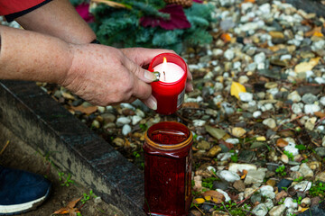 Liebevolle Grabpflege im Herbst, Herbstlaub beseitigen und Kerze aufstellen.