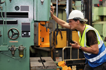 Technician engineer or worker in protective uniform standing and repairing operation or checking industry machine process with safety hardhat at heavy industry manufacturing factory