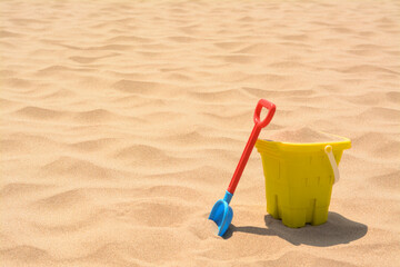 Fototapeta na wymiar Plastic bucket and shovel on sand, space for text. Beach toys
