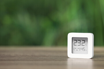 Digital hygrometer with thermometer on table against blurred background. Space for text