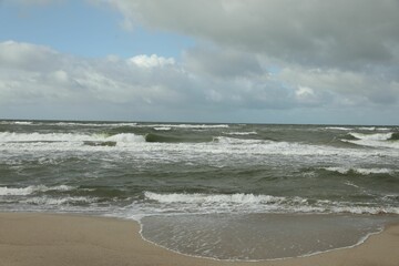 Fototapeta na wymiar Picturesque view of wavy sea on cloudy day