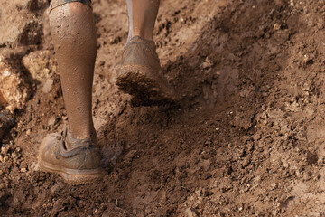 Mud race runner very muddy running shoes, muddy feet detail