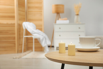 Wooden table with candles and cup, space for text. Interior design