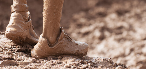 Mud race runner very muddy running shoes, muddy feet detail