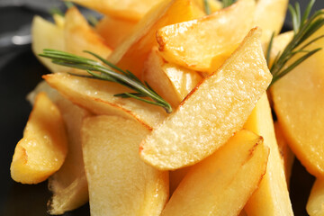 Tasty baked potato wedges and rosemary, closeup