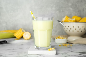 Tasty fresh corn milk in glass on white marble table