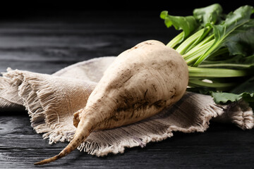 Fresh sugar beet with leaves on black wooden table, closeup