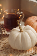 Pumpkins and hot drink on wicker mat indoors