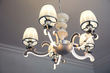 Stylish chandelier on ceiling in light room