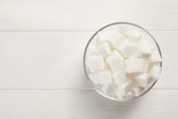 Bowl with sugar cubes on white table, top view. Space for text