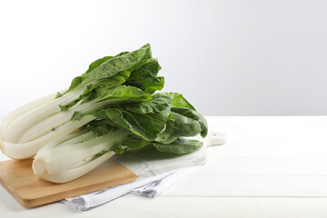 Fresh green pak choy cabbages on white wooden table, space for text