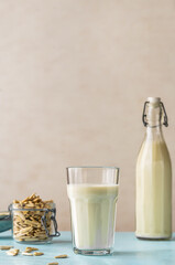 Sunflower milk in a glass and bottle, raw sunflower seeds in jar on light blue background