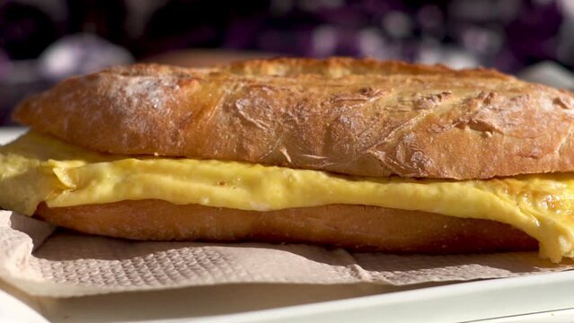 slow motion, sandwich with omellet on a white plate, outdoors