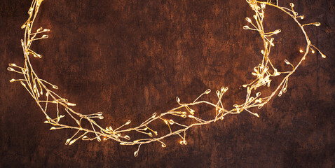 Christmas lights on adark woodeen background. Golden Xmas decorations glowing.garland top view,...