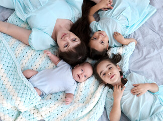 Young mother with her daughters and newborn baby. Lovely brother and sisters together. Family relationship.