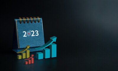Happy new year 2023 background. 2023 numbers year with goal target icon on blue small desk calendar with 3d growing graphs isolated on black background with copy space, minimalist. Start a new goals.