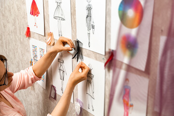 Woman fashion designer is working on creating sketches of dresses. Design and tailoring. Seamstress in the studio.