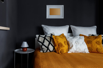 Steal with pillows and yellow bedspread in dark apartments - obrazy, fototapety, plakaty