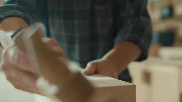 Close-up of Artisan Craftsman Hands Using Hand Plane to Shape a Wood Bar. Carpenter Working on a Project in a Woodworking Workshop. Manual Labor. Carpentry, Craftsmanship, and Handwork Concept.