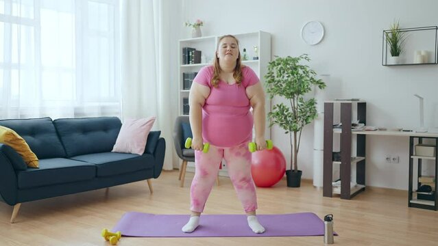 Lazy obese woman doing dumbbell exercise at home, training to lose weight