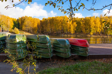 Boats at the boat station. The end of the season. Green and red boat. Sunny autumn day.