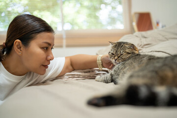 In the bedroom there was a gray tabby lying on the bed. and a woman's hand gently caressed her...