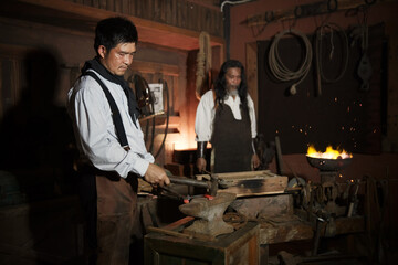 vintage style portraits Two cowboys fixing horseshoes in the smithy.
