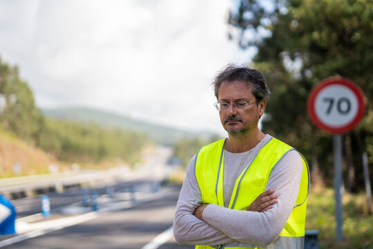 Caucasian Man Waiting A Mechanic To Come Fix His Broken Down Vehicle On The Highway Wearing A Reflective Vest