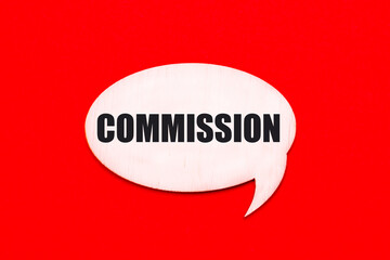 On a bright red background, a light wooden curly card with the text COMMISSION