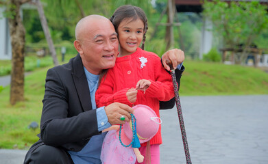 Senior man and graddaughter enjoy being together in park.