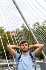 A young happy caucasian man relaxed in the Bilbao bridge in the street with closed eyes