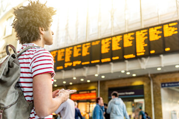 Man waiting for train and using phone at train station in London - obrazy, fototapety, plakaty