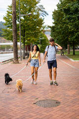 A young happy caucasian couple walking their dogs in a cloudy day in Spain in Bilbao and staring at the camera