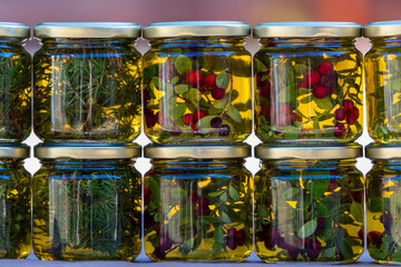 Jars of honey with forest herbs and green spruce needles stand on a local street market in a row....