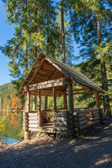 Wooden gazebo for relaxation near Lake Synevyr next to the autumn forest in the Carpathian mountains on a sunny autumn day. Ukraine