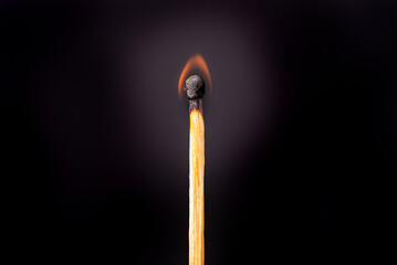 Matchstick burning in detail seen through a macro lens, black background, selective focus.