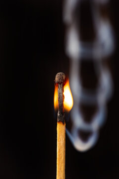 Matchstick burning in detail seen through a macro lens, black background, selective focus.