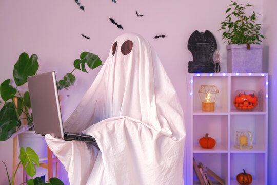The ghost of Halloween uses a laptop to surf the Internet, to browse online stores, markets. A ghost makes an order computer for Halloween. The ghost pays for an online purchase. Neon light.
