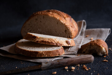 Loaf of bread freshly baked and cut on dark background