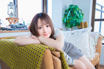ソファーに寄りかかりながらこちらを見つめる日本の若い女性