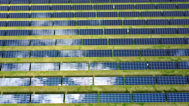 Luftbild von Sonnenkollektoren, die Wolken eines Solarparks reflektieren, w&auml;hrend eines &Uuml;berflugs mit 4k durch eine Drohne