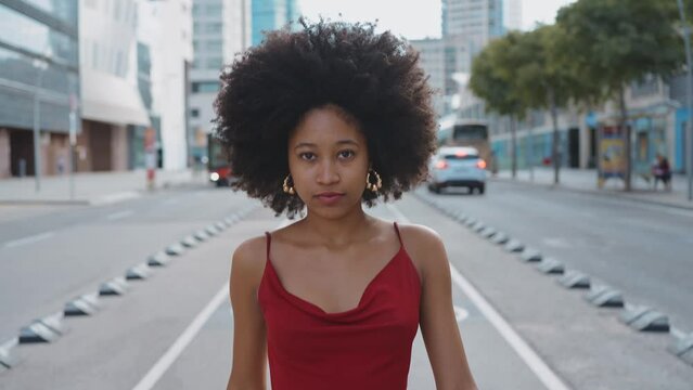 Cinematic video of a self confident young woman spending time in a modern city. Millennial girl with afro hairstyle lifestyle moments.