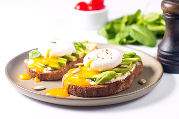 Toast with avocado, soft cream cheese, rye bread and poached Egg. Wholemeal open sandwich for healthy breakfast concept.