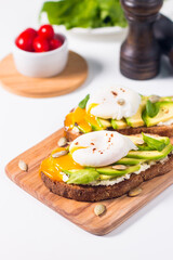 Toast with avocado, soft cream cheese, rye bread and poached Egg. Wholemeal open sandwich for healthy breakfast concept.