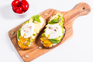 Toast with avocado, soft cream cheese, rye bread and poached Egg. Wholemeal open sandwich for healthy breakfast concept.