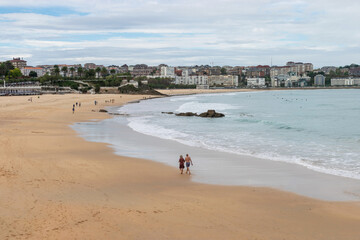 Fototapeta na wymiar Couple walking along the Sandinero Beach. Santander