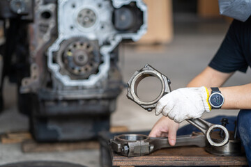Mechanic man holding piston rod of diesel commonrail engine in heavy machinery workshop